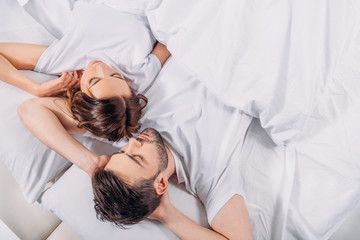 overhead view of young couple sleeping in bed together