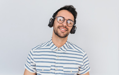 Candid shot of handsome happy young male wearing striped shirt and trendy glasses, with headphones...