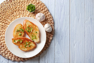 Plate with delicious homemade garlic bread on table