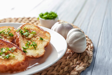 Plate with delicious homemade garlic bread on table