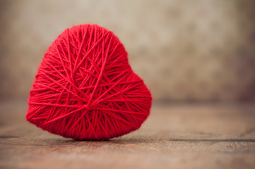 closeup of red woolen heart on wooden table background