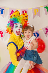 clown girl on the birthday of a child. A party for a child. Keep the baby in your arms