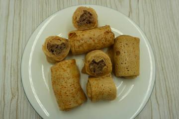 Pancakes with meat on the wooden table .