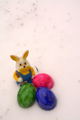 Osterhase und bunte Eier im Schnee.