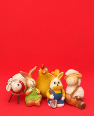 Osterfiguren Schafe, Hasen, Osterhase, Küken vor rotem Hintergrund. Hochformat. 