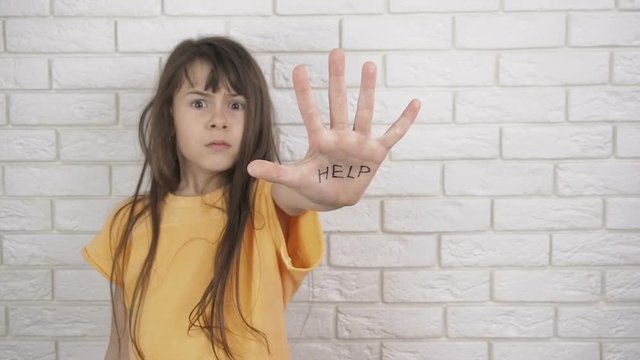 Fear of the child. Child abuse. Domestic violence. The inscription on the hand- Help. A frightened child asks for help.