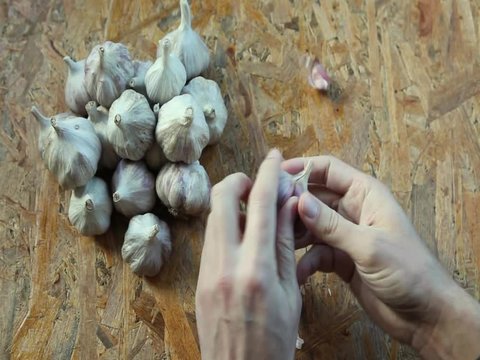 hands of man which clean and sort garlic on a wooden surface