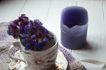 Violet flowers in a cup on a dining table.