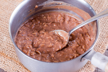 Cooking chocolate oatmeal porridge in a saucepan