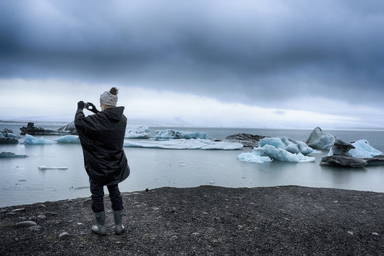 Woman taking a picture of icebergs her phone