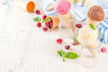 Summer sweet berries and desserts, various of ice cream flavor in cones pink (raspberry), vanilla and chocolate with mint on light concrete background copy space