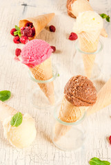 Obraz na płótnie Canvas Summer sweet berries and desserts, various of ice cream flavor in cones pink (raspberry), vanilla and chocolate with mint on light concrete background copy space