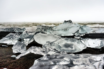 Lots of pieces of ice rocks on black sand 