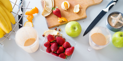 Fresh strawberries green apples and bananas being cut and blended into a fresh fruit smoothie.