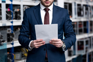 cropped shot of young businessman with paperwork at cryptocurrency mining farm