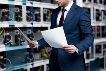 handsome young businessman reading documents at cryptocurrency mining farm