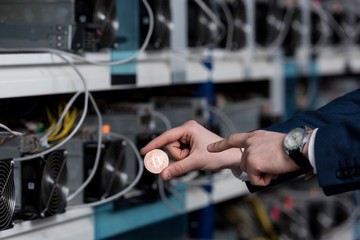 cropped shot of businessman pointing at bitcoin at cryptocurrency mining farm