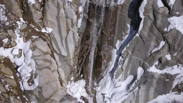 Aerial view of Lisa Falls waterfall in winter flying towards the top of the cliffs.