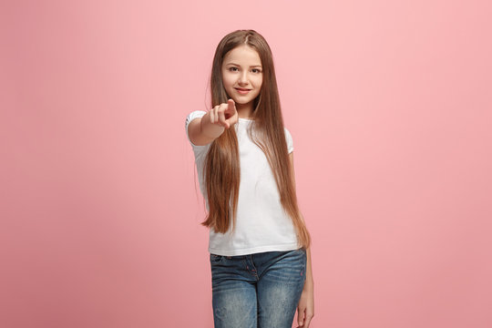 The happy teen girl pointing to you, half length closeup portrait on pink background.