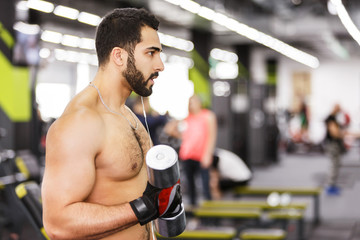 Fototapeta na wymiar Topless bearded man holds metal dumbbell in the gym
