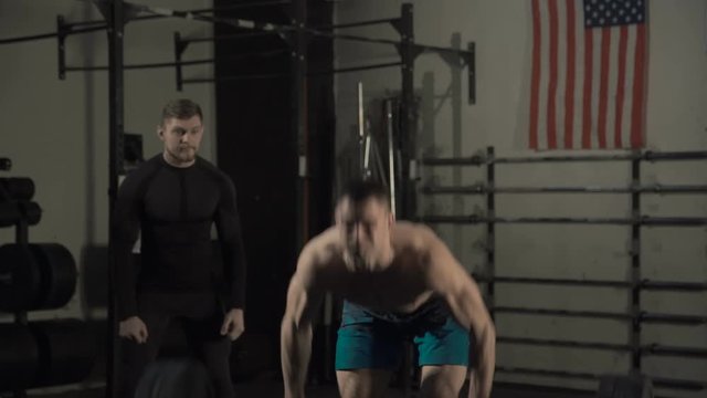 Athletic men training in together in gym and doing powerlifting exercise supporting each other.