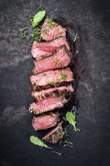 Tuinposter Barbecue wagyu point steak slices with lettuce and herbs as top view on a board with copy space © HLPhoto