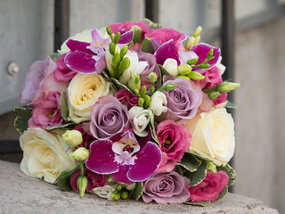 Beautiful bouquet of white and purple roses, violet orchids and freesias on a blurry background