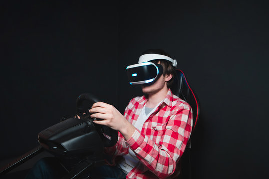 A man plays a race with a vr headset on a car simulator. Games in glasses of virtual reality. Three-dimensional image.