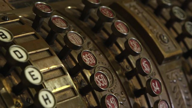 Panning view of old cash register moving over the buttons showing the dollar signs.