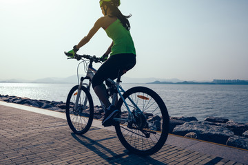 Fototapeta premium female cyclist riding mountain bike on seaside