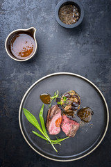 Traditional Italian barbecue aged sliced fillet steak with wild garlic and pioppinos as top view on a plate with copy space