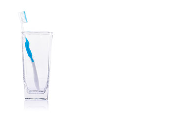 White toothbrush in a clear glass on white background