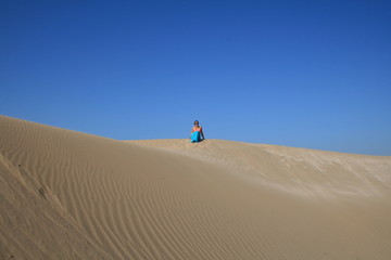 Young woman in blue skirt in sand dunes