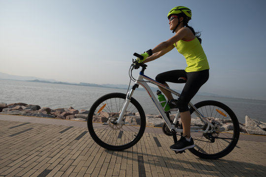 female cyclist riding mountain bike on seaside