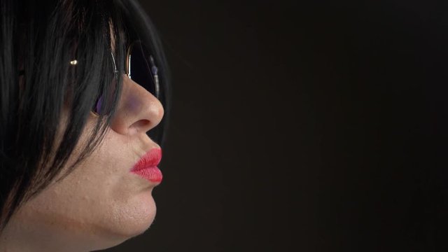 Hot brunette in round sunglasses, chewing gum and blowing a bubble. 4k, slow motion.
