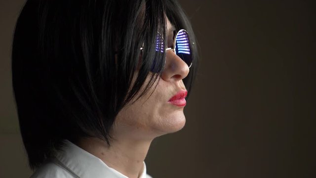 Hot brunette in round sunglasses, chewing gum and blowing a bubble. 4k, slow motion.