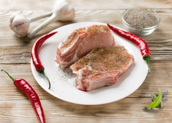 Raw pork ribs with red pepper, garlic and seasonings on a wooden background.