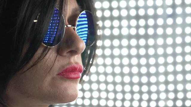 Hot brunette in round sunglasses, chewing gum and blowing a bubble. 4k, slow motion.