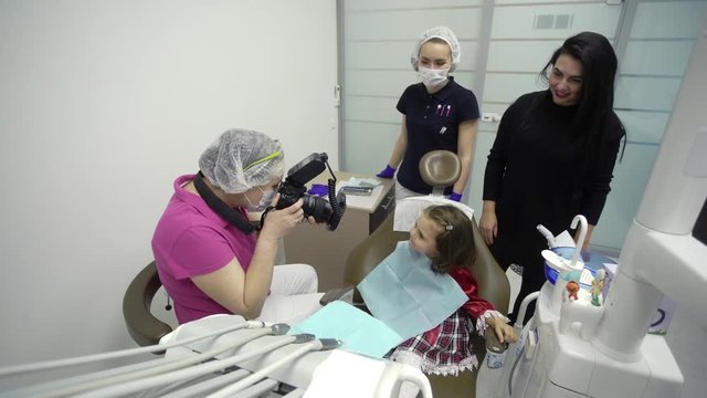 Child girl in dental clinic in dentist chair with doctor taking photos of teeth