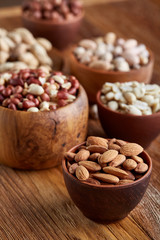 A composition from different varieties of nuts in a wooden bowls on rustic background, close-up, shallow depth of field