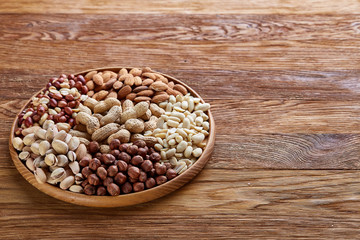 Mixed nuts arrenged on wooden tray over rustic background, close-up, selective focus.