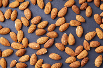 Seamless pattern with almond on the dark gray background, flat lay, close-up.