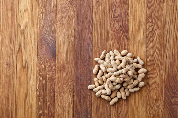 Unpeeled peanuts on a wooden background, top view, selective focus, shallow depth of field.