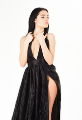 Fototapeta premium Sexy decollete concept. Lady, sexy girl in dress. Woman in elegant black evening dress with decollete, white background. Attractive girl wears expensive fashionable evening dress with erotic slit.