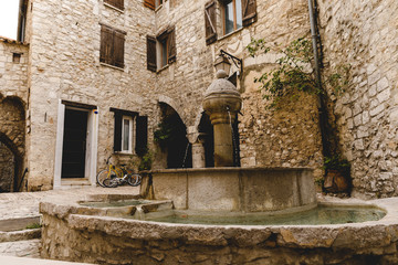Fototapeta na wymiar atrium of ancient buildings at old town with beautiful fountain, Peille, France