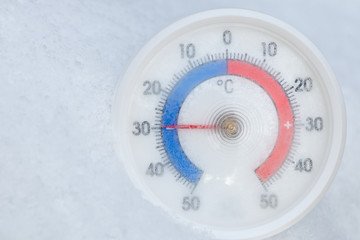 Naklejka premium Outdoor thermometer in snow shows minus 30 Celsius degree extreme cold winter weather concept