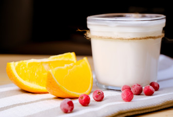 A jar of homemade yoghurt with fresh cranberries, fresh orange