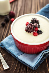 Semolina porridge with raspberries on rustic wooden background