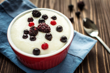 Semolina porridge with raspberries on rustic wooden background