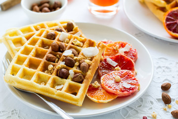 Healthy breakfast. Belgian waffles with nuts and sicilian oranges on the white table
